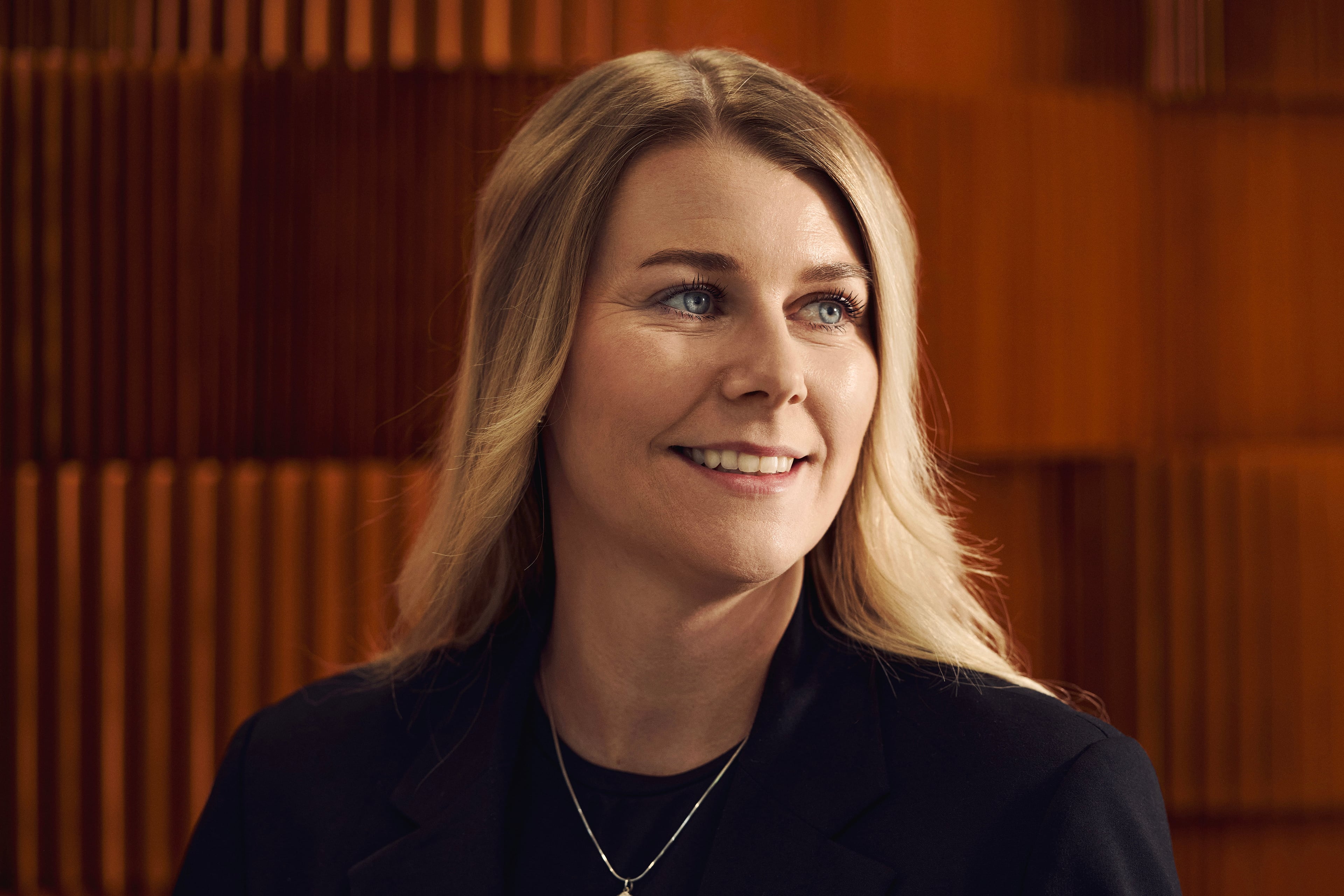 Woman with light hair smiling at camera in front of orange wall panel