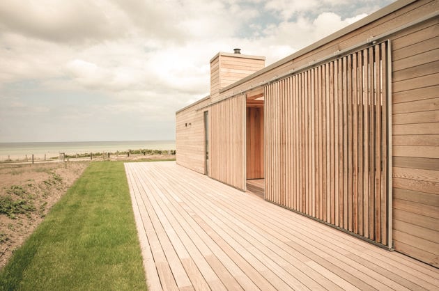 Modern wooden building with terrace overlooking fields and sea
