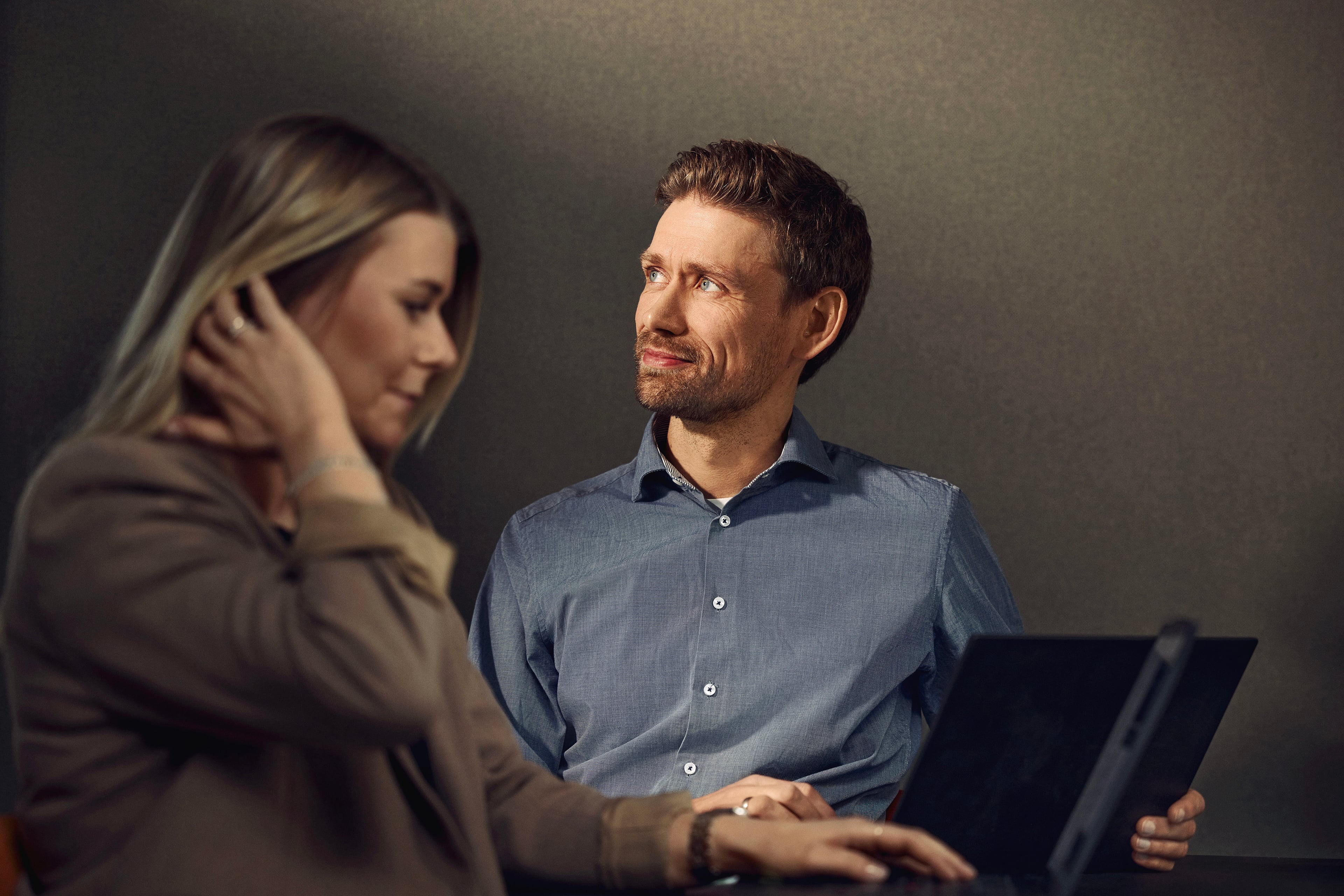 Man and woman working together on a tablet against a neutral background