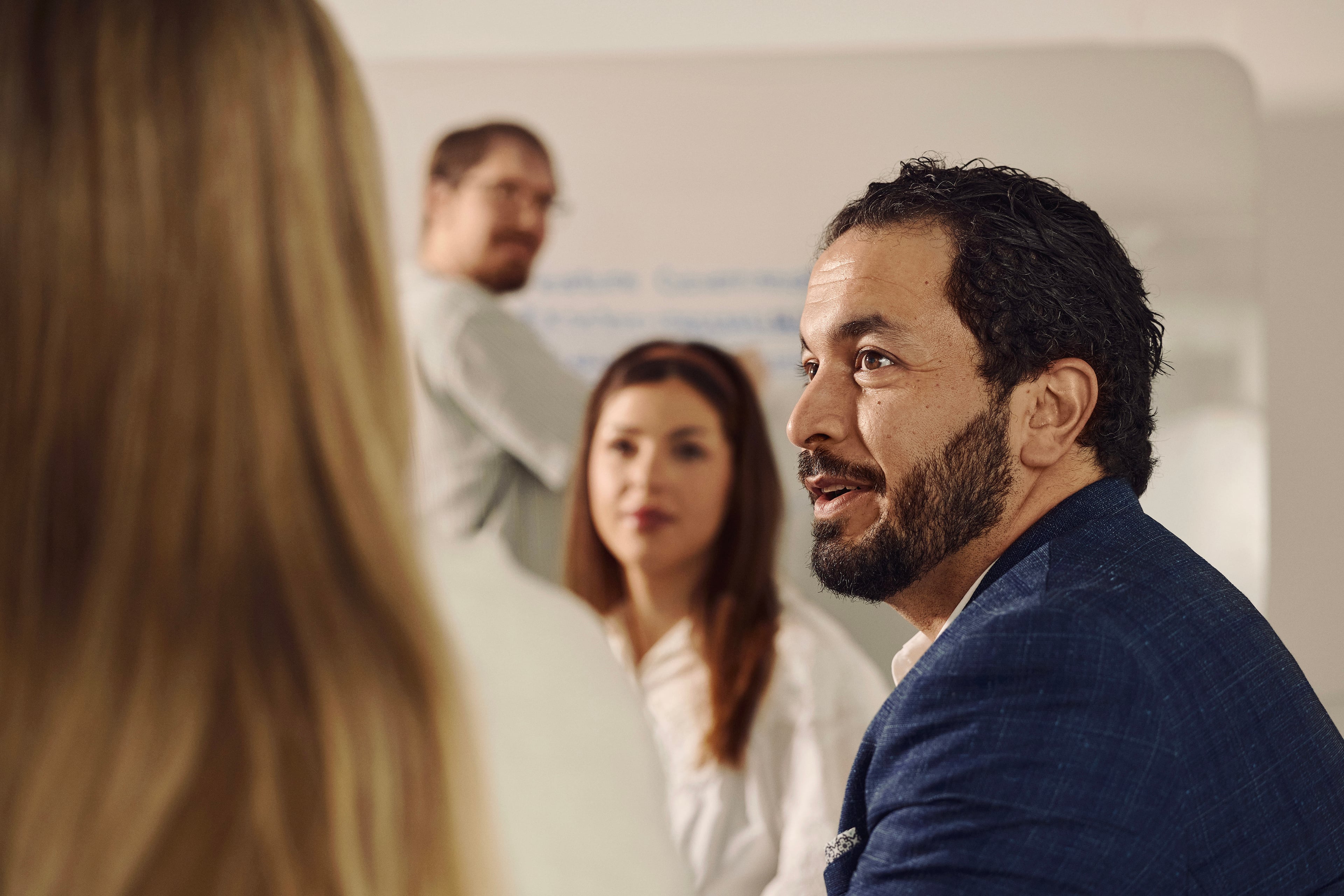 Man listening to colleague in meeting with four people in conference room
